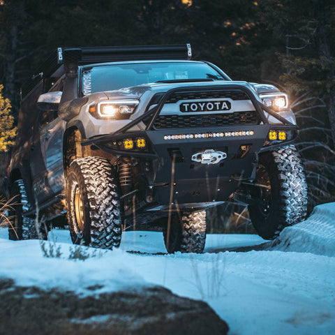 Tacoma off-roading in the snow and equipped with a pop-top topper and C4 Hybrid front bumper.